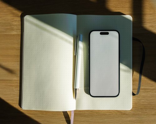 Cell phone and notebook neatly placed on a wooden desk